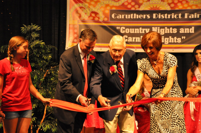 three people on stage cutting ribbon with scissors