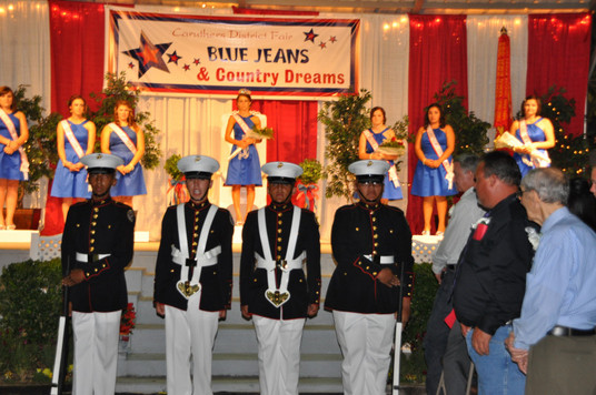 girls on stage and men in uniform standing in front of stage