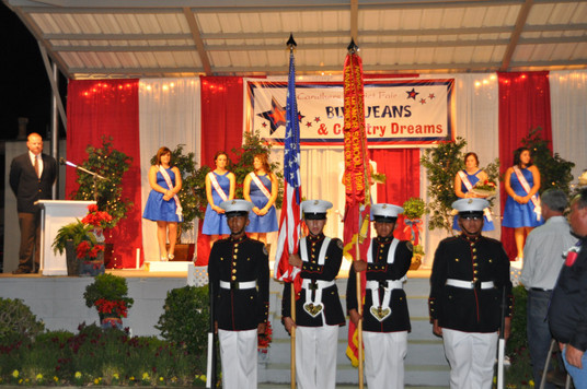 girls on stage and men in uniform holding american flag