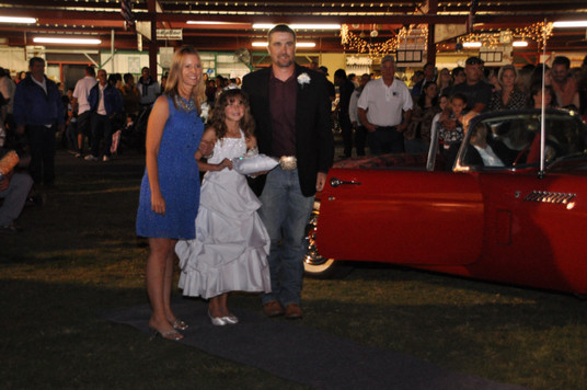 young girl standing in front of red convertible with her parents