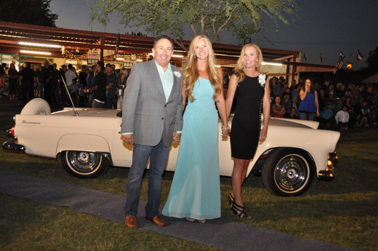 girl holding hands with her parents in front of classic convertible car