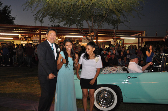 girl standing in front of classic convertible car with her parents