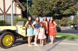 5 girls posing in front of old fashioned car