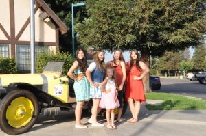 5 girls posing in front of old fashioned car