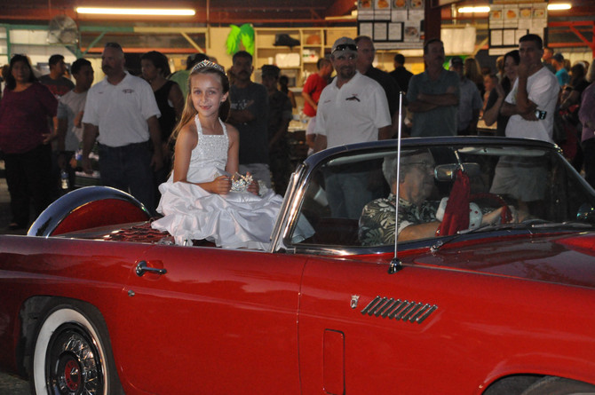 young girl with crown sitting on classic convertible car
