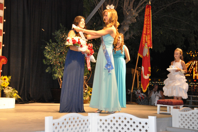girl placing sash on another girl on stage
