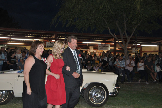 girl linking arms with parents in front of classic convertible car
