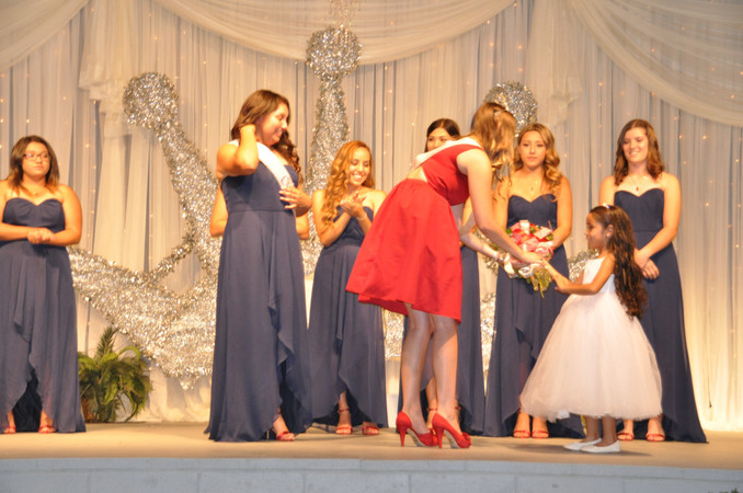 young girl handing bouquet of flowers to another girl on stage