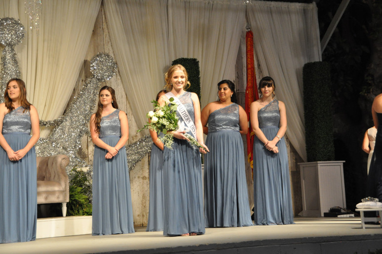 girl with sash and bouquet of flowers on stage with other girls