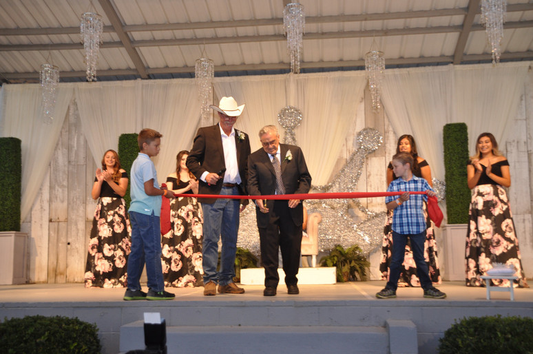 man cutting red ribbon on stage