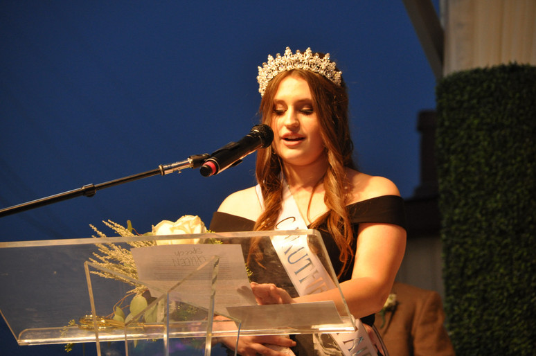 girl with crown and sash speaking at podium